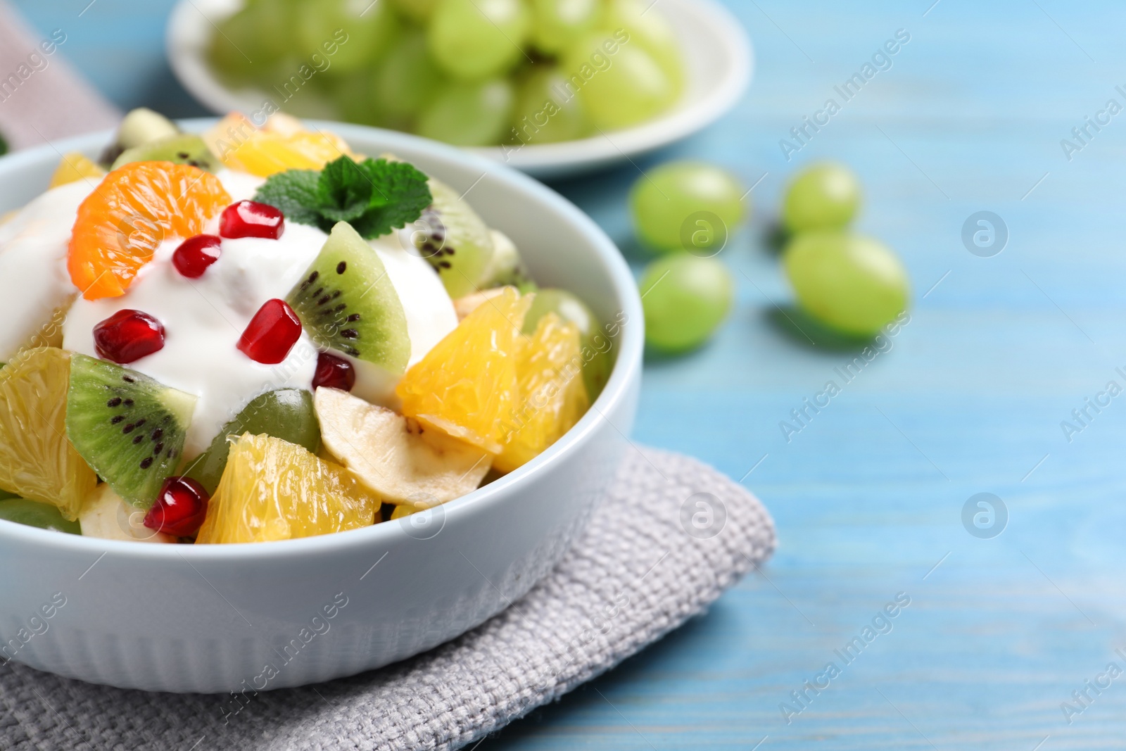 Photo of Delicious fruit salad on light blue wooden table, space for text