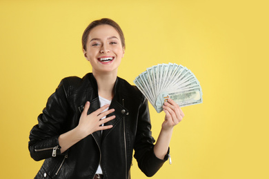 Young woman with money on yellow background