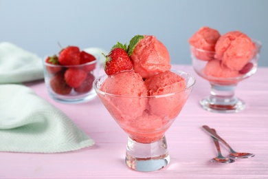 Delicious strawberry ice cream in dessert bowl served on pink wooden table