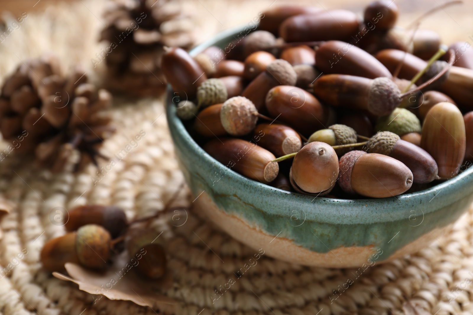 Photo of Acorns in bowl on wicker mat, closeup