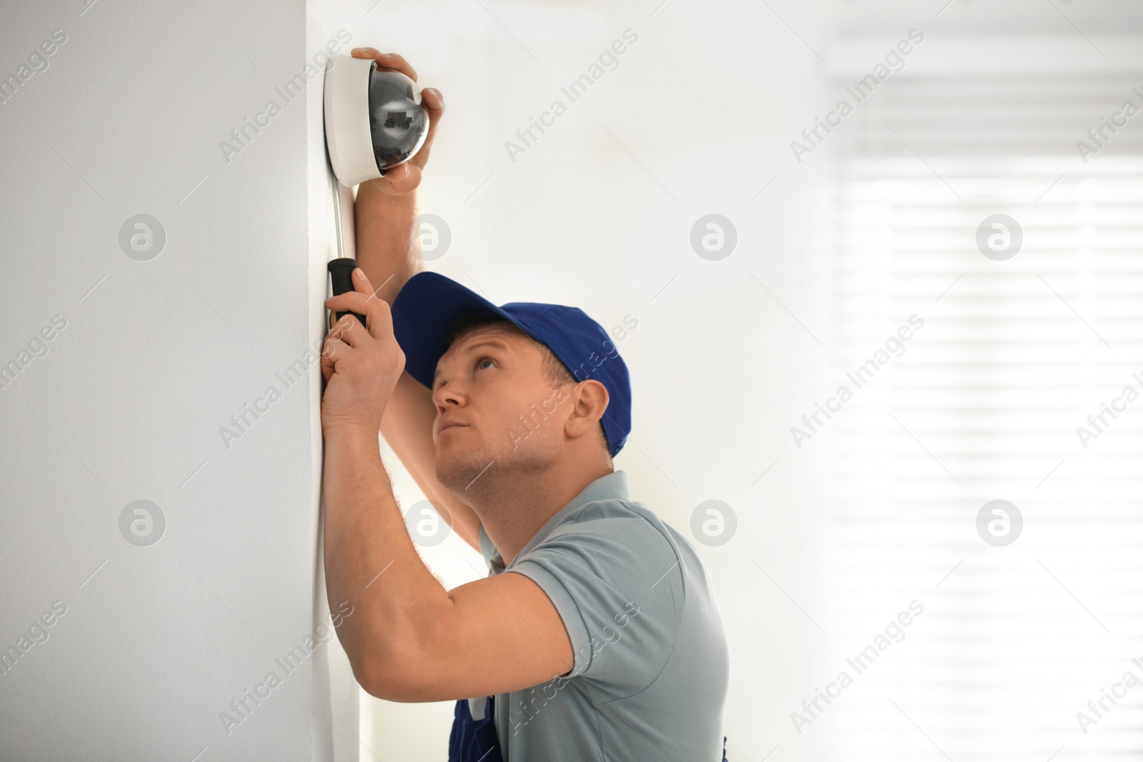 Photo of Technician installing CCTV camera on wall indoors