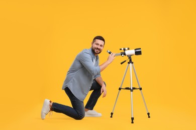 Photo of Happy astronomer with telescope on orange background