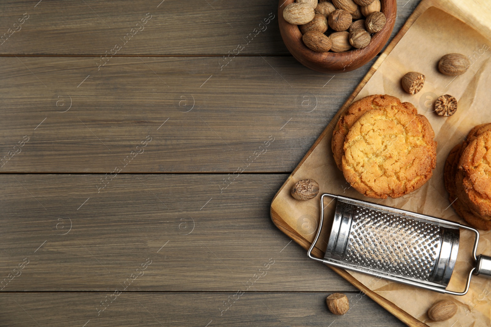 Photo of Tasty cookies, nutmeg seeds and grater on wooden table, flat lay. Space for text