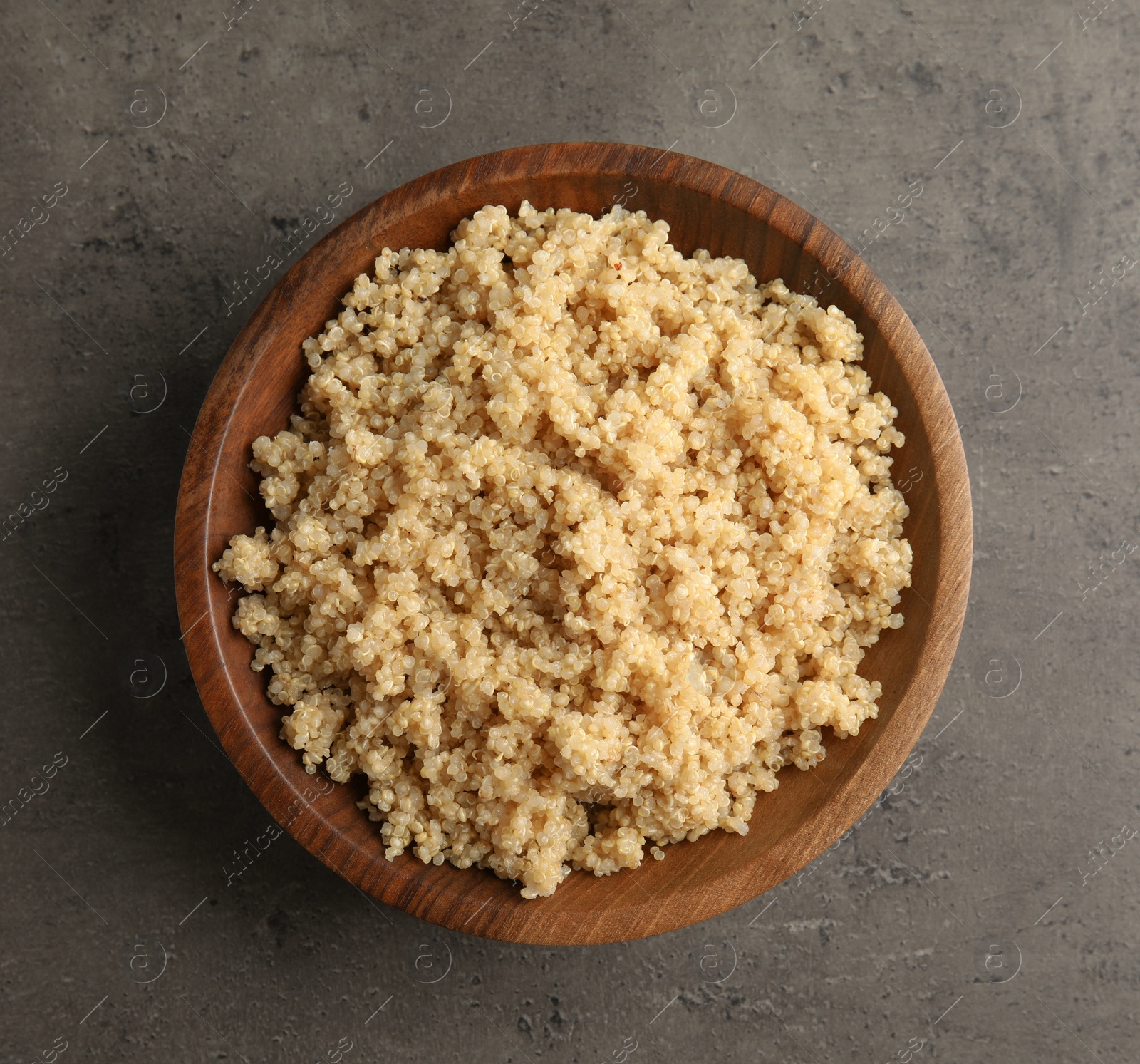 Photo of Cooked delicious quinoa in wooden bowl on table, top view