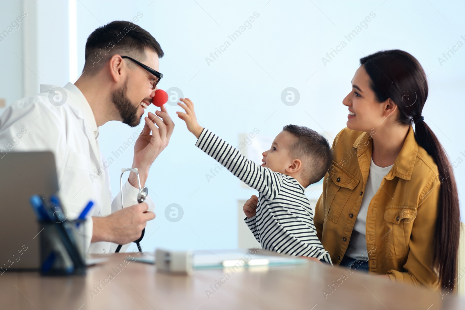 Photo of Mother and son visiting pediatrician in hospital. Doctor playing with little boy