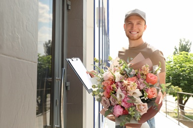 Delivery man with beautiful flower bouquet near front door