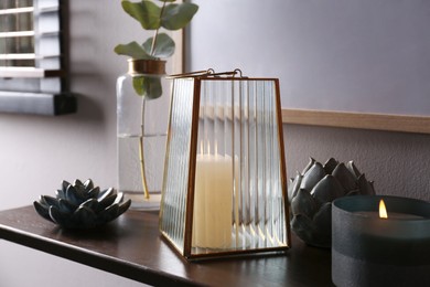 Stylish glass holder with candle and decor on wooden table indoors