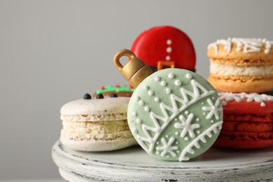 Photo of Beautifully decorated Christmas macarons against light grey background, closeup. Space for text