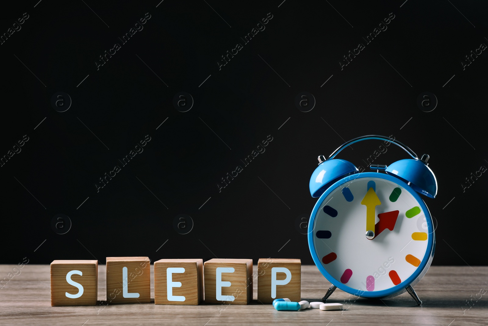 Photo of Word Sleep made with cubes, alarm clock and pills on wooden table, space for text. Insomnia treatment