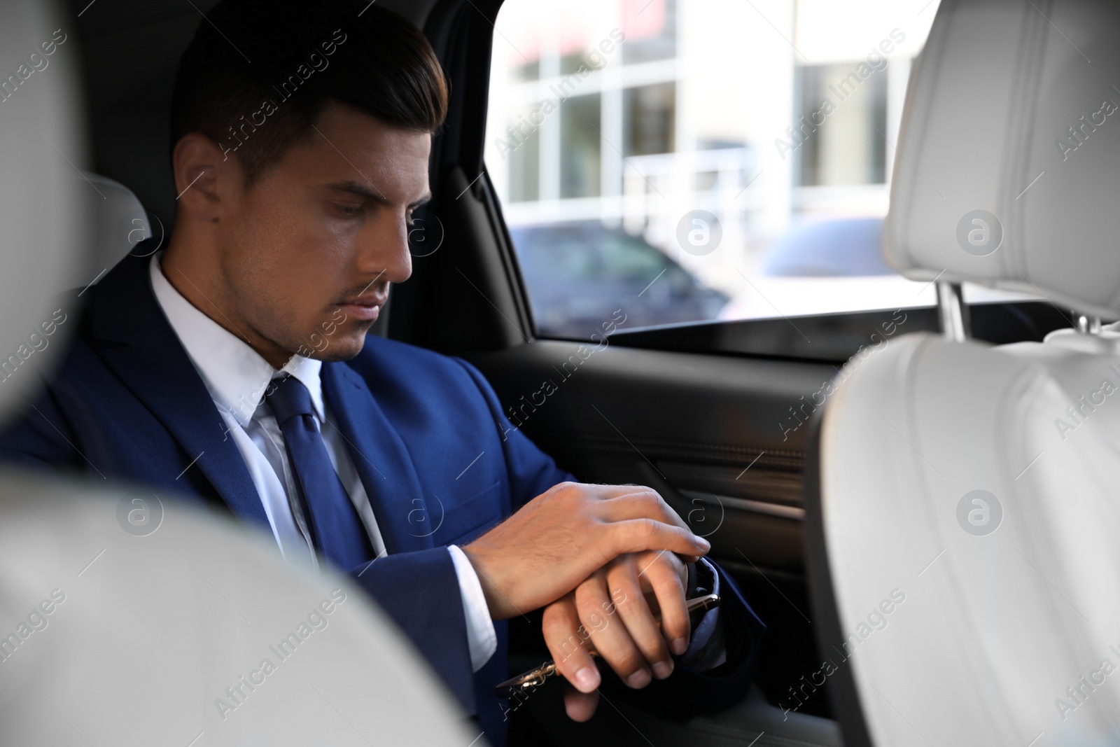 Photo of Handsome man with smartphone on backseat of modern car