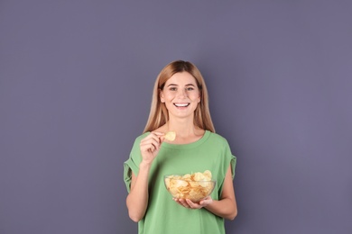 Photo of Woman eating potato chips on grey background