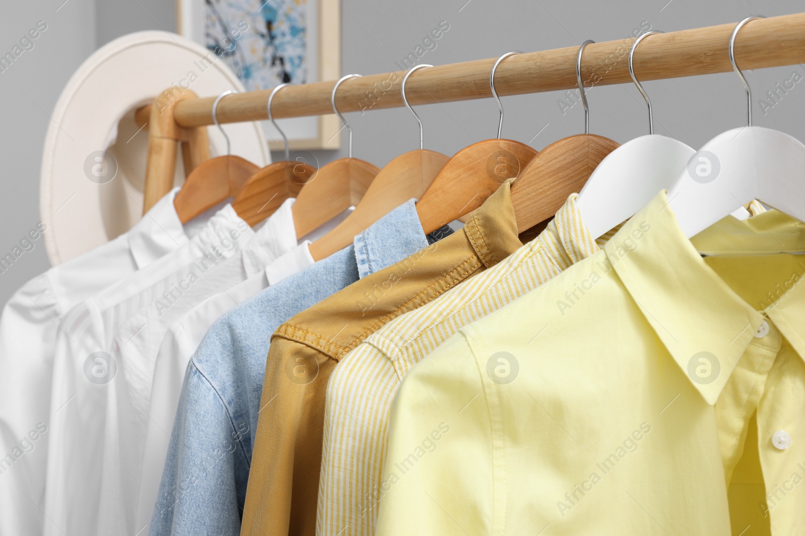 Photo of Rack with different stylish shirts near grey wall, closeup. Organizing clothes