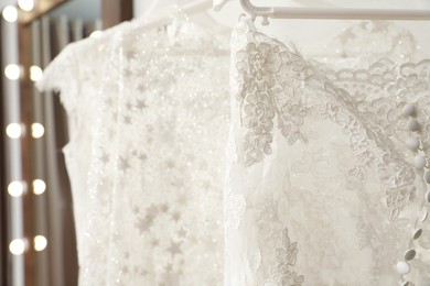 Photo of Beautiful wedding dresses hanging in boutique, closeup