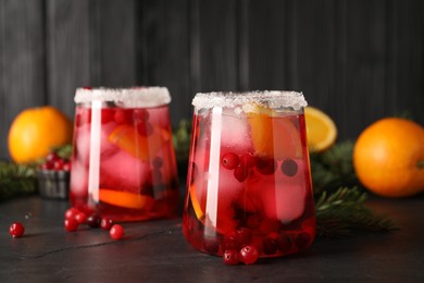 Photo of Tasty cranberry cocktail with ice cubes in glass on dark gray table