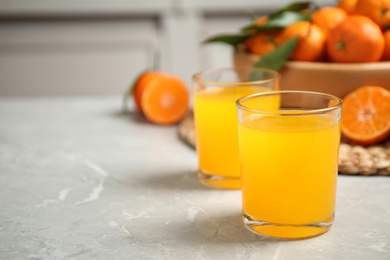 Photo of Glasses of fresh tangerine juice on marble table. Space for text