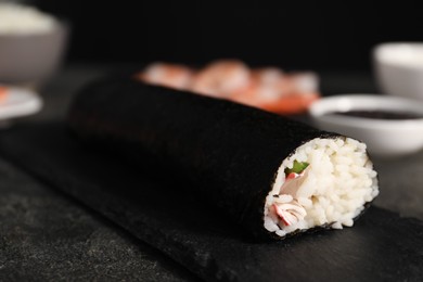 Photo of Tasty sushi roll on dark textured table, closeup