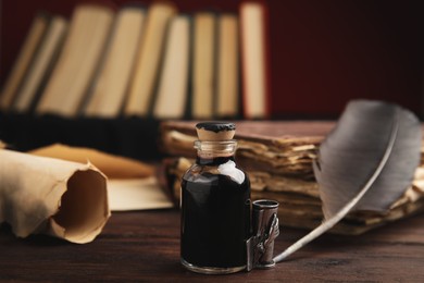 Photo of Feather pen and bottle of ink on wooden table