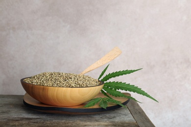 Bowl with hemp seeds on table against grey background