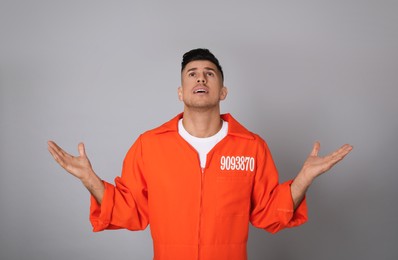 Photo of Prisoner in orange jumpsuit on grey background