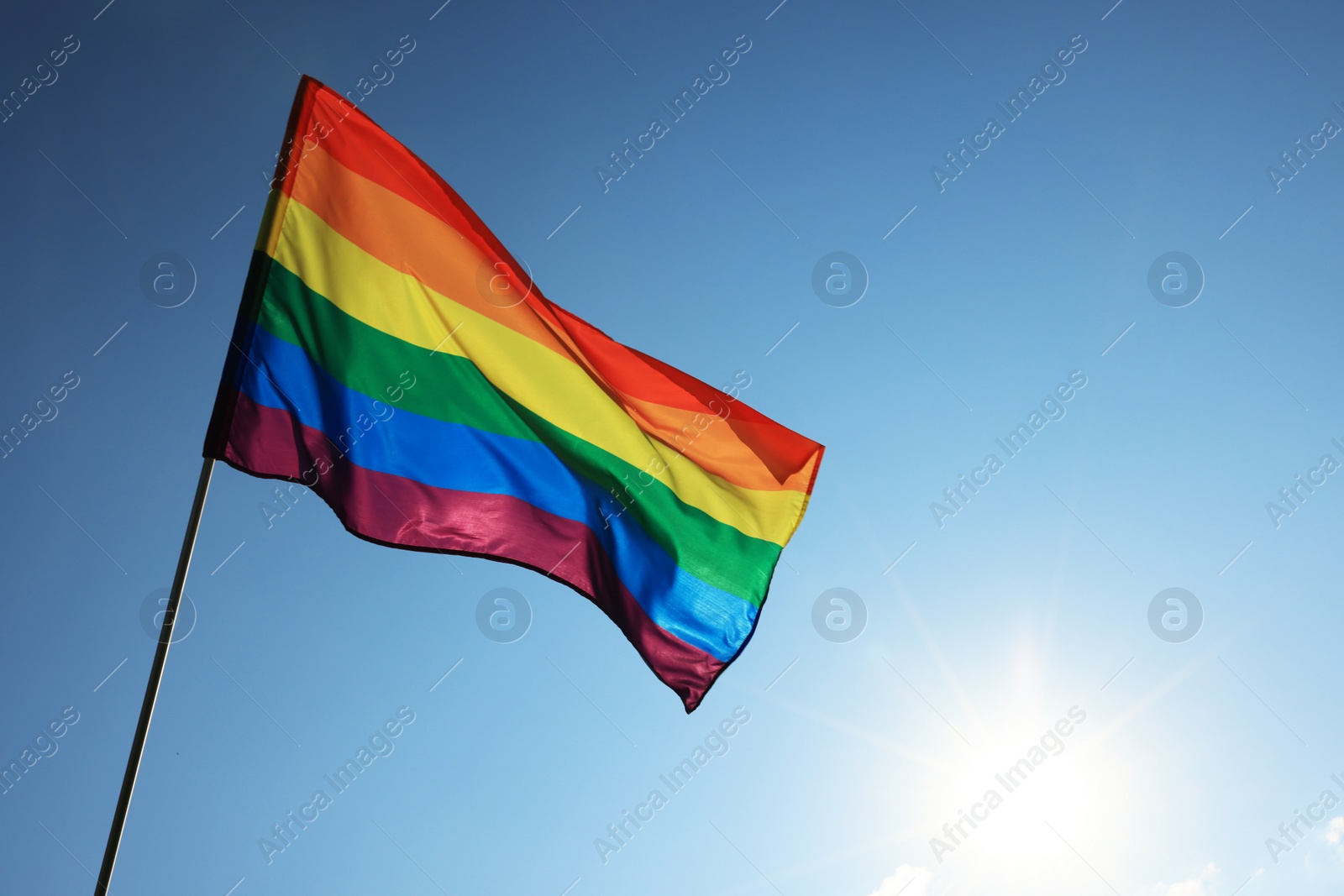 Photo of Bright LGBT flag fluttering against blue sky