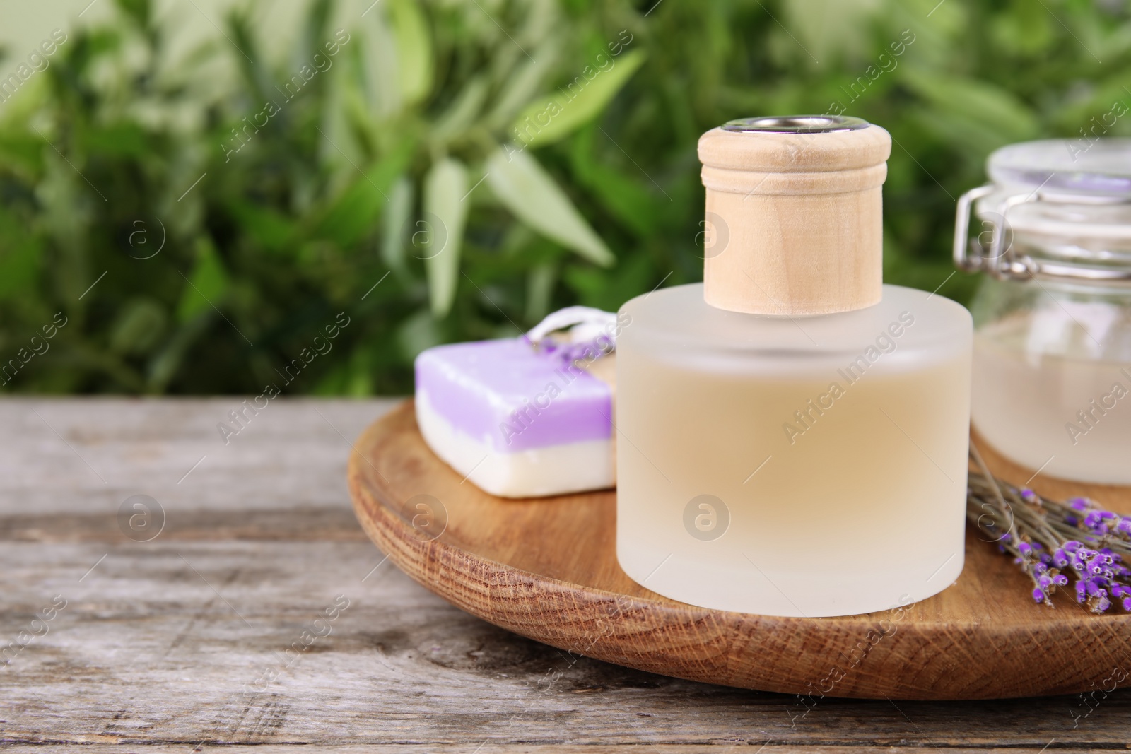 Photo of Natural herbal oil and lavender flowers on table against blurred background. Space for text