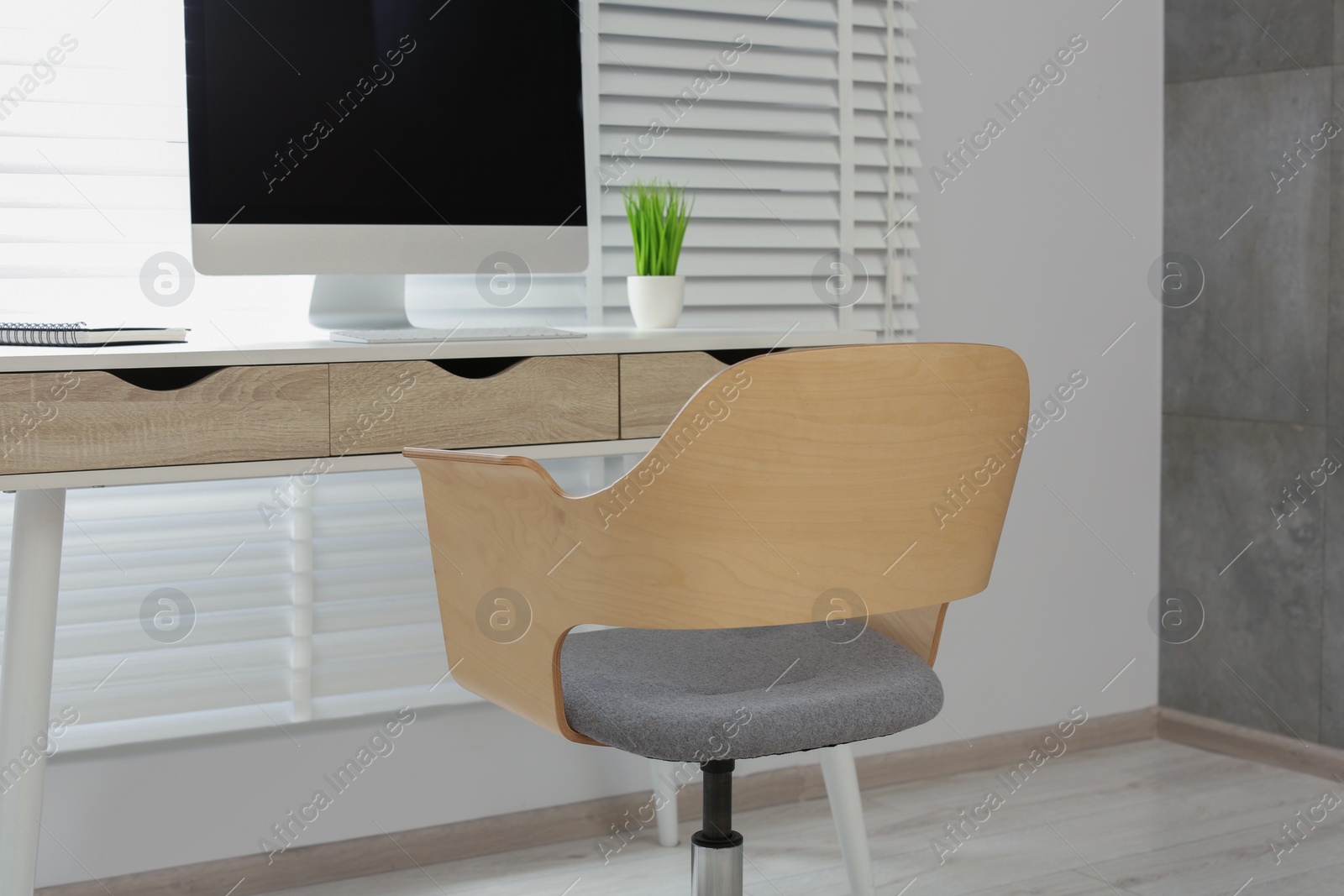 Photo of Stylish office interior with comfortable chair, desk and computer