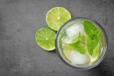 Refreshing beverage with mint and lime in glass on grey background, top view