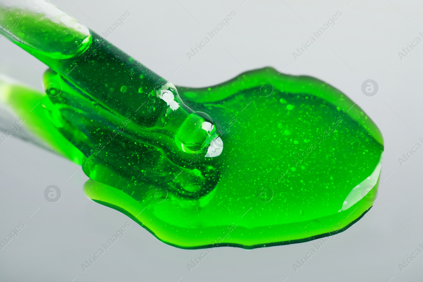 Photo of Dripping green serum from pipette on mirror, closeup