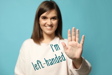 Image of Left-handed woman against light blue background, focus on palm 