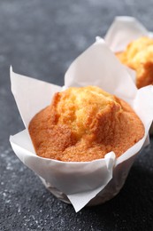 Photo of Delicious sweet muffins on black textured table, closeup