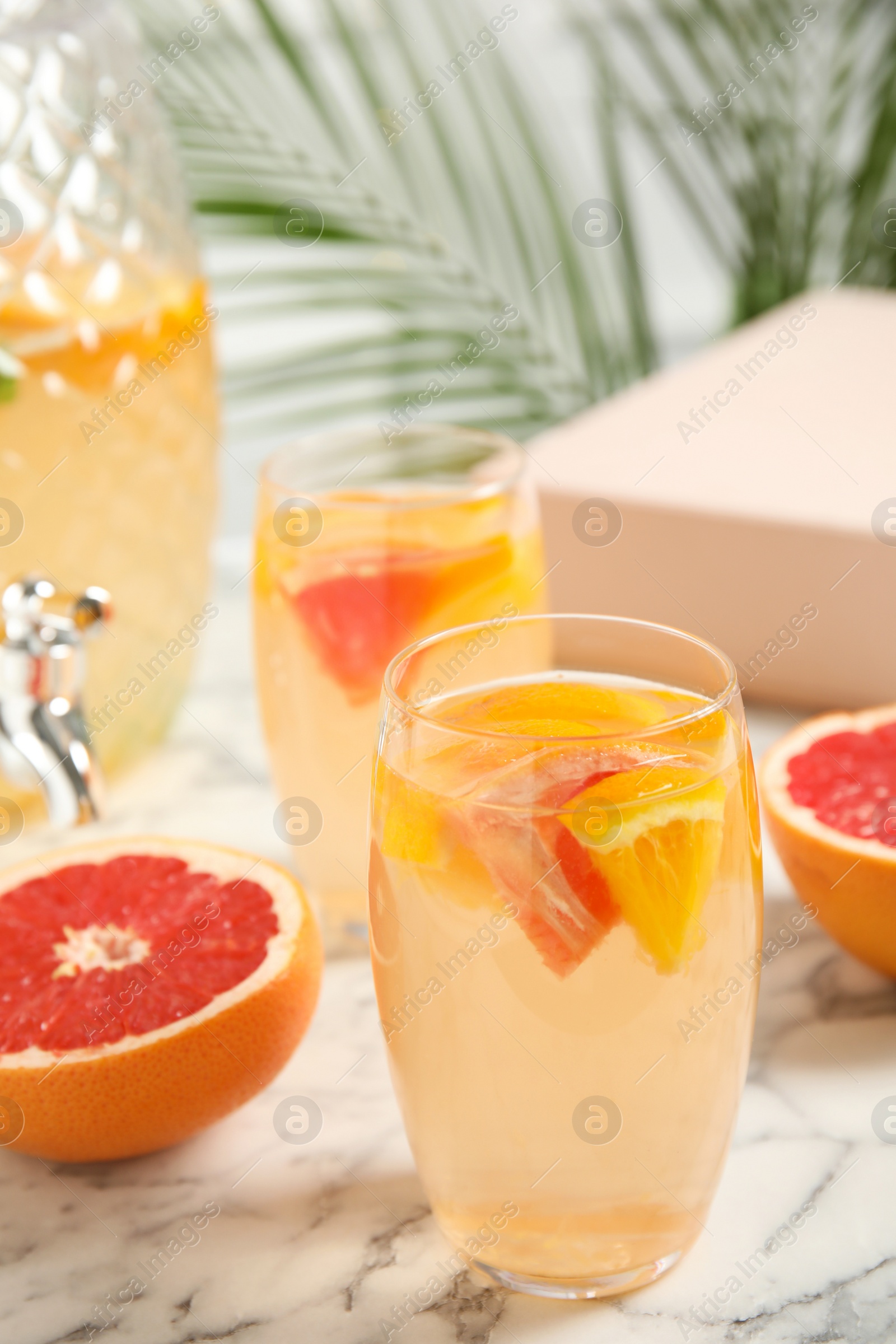 Photo of Delicious refreshing drink with orange and grapefruit on white marble table