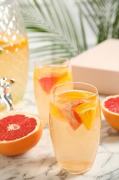 Delicious refreshing drink with orange and grapefruit on white marble table