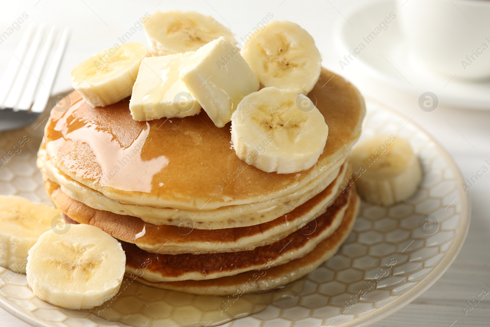 Photo of Delicious pancakes with bananas, honey and butter on white wooden table, closeup