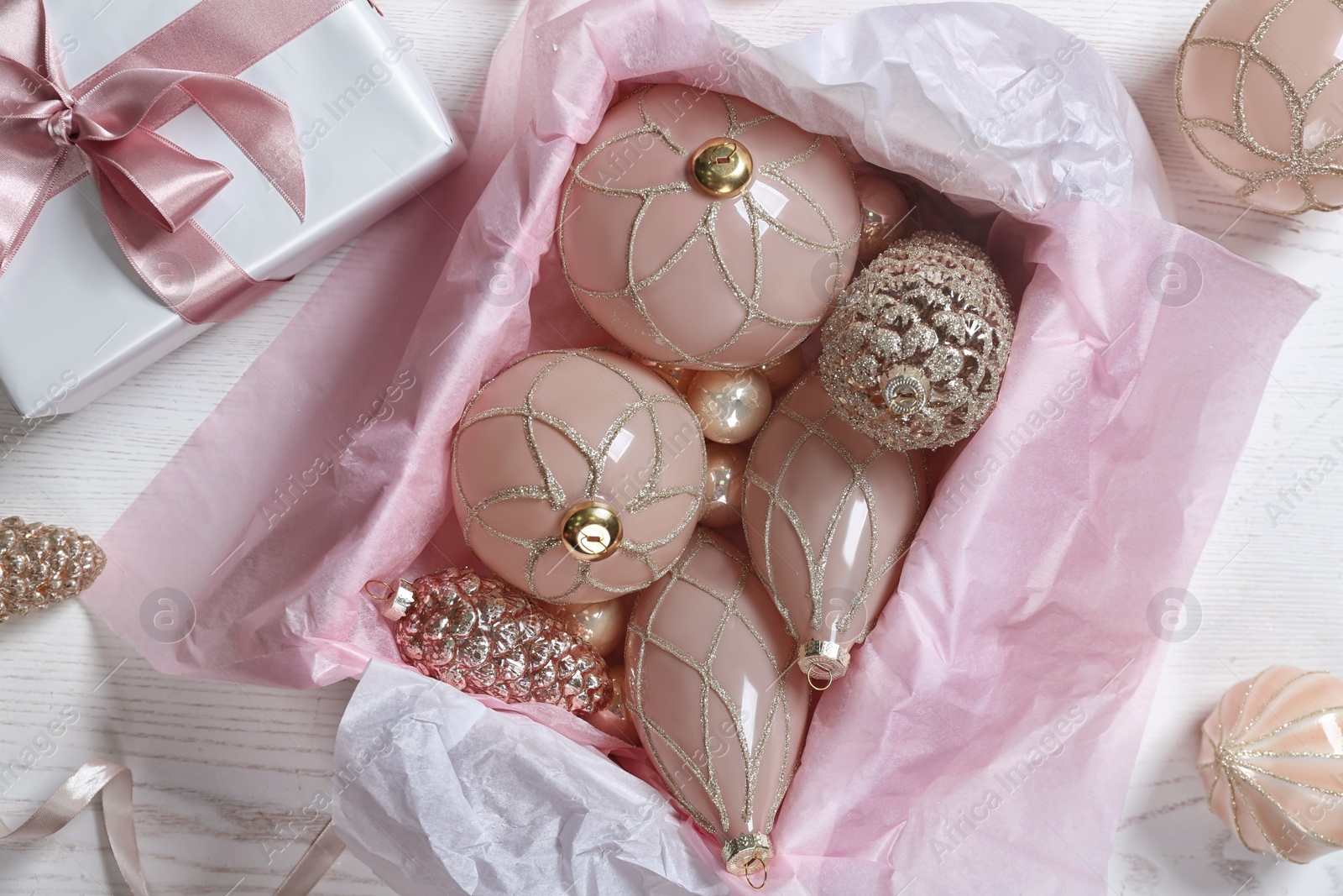 Photo of Collection of beautiful Christmas tree baubles and gift box on white wooden table, flat lay