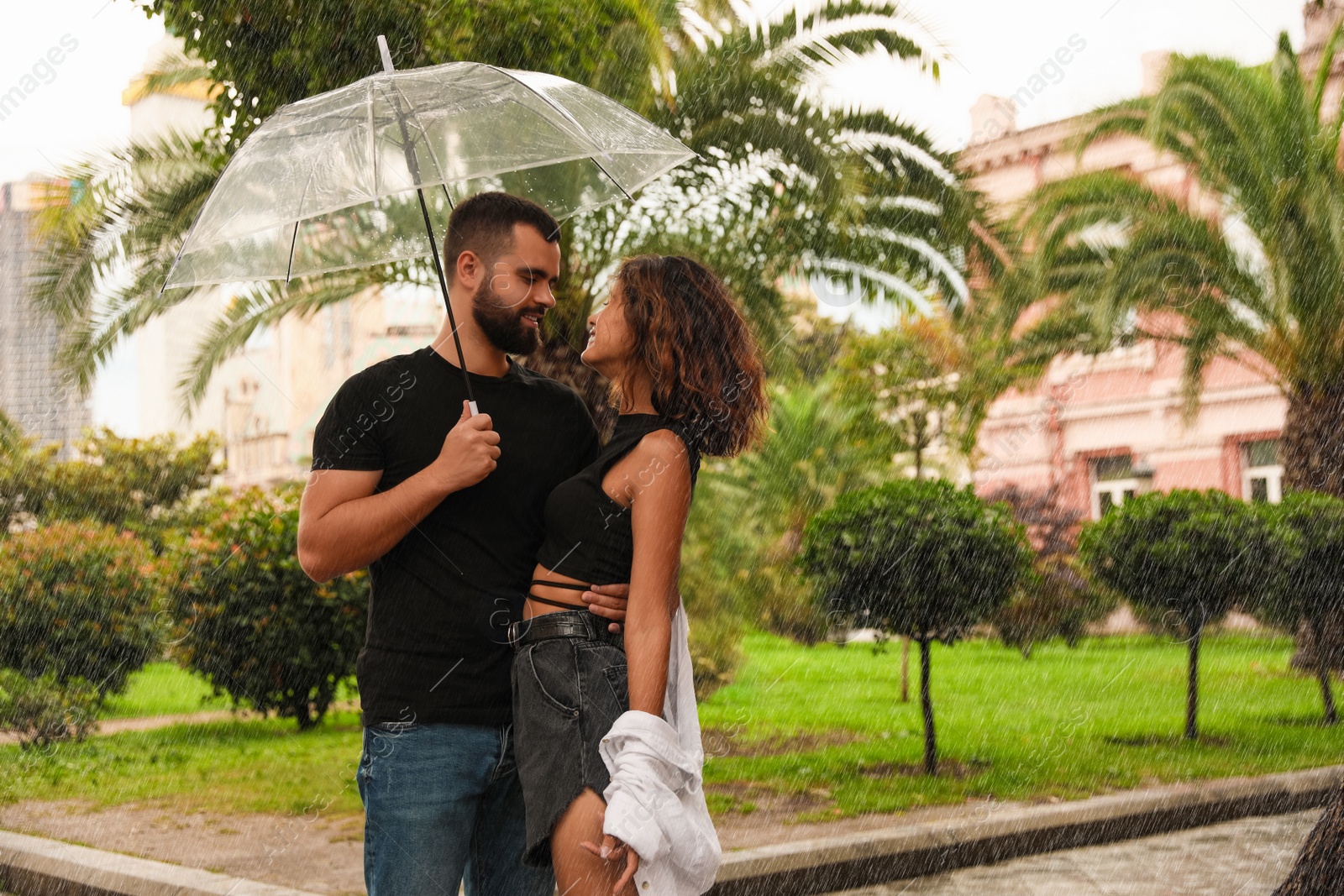 Photo of Young couple with umbrella enjoying time together under rain on city street, space for text