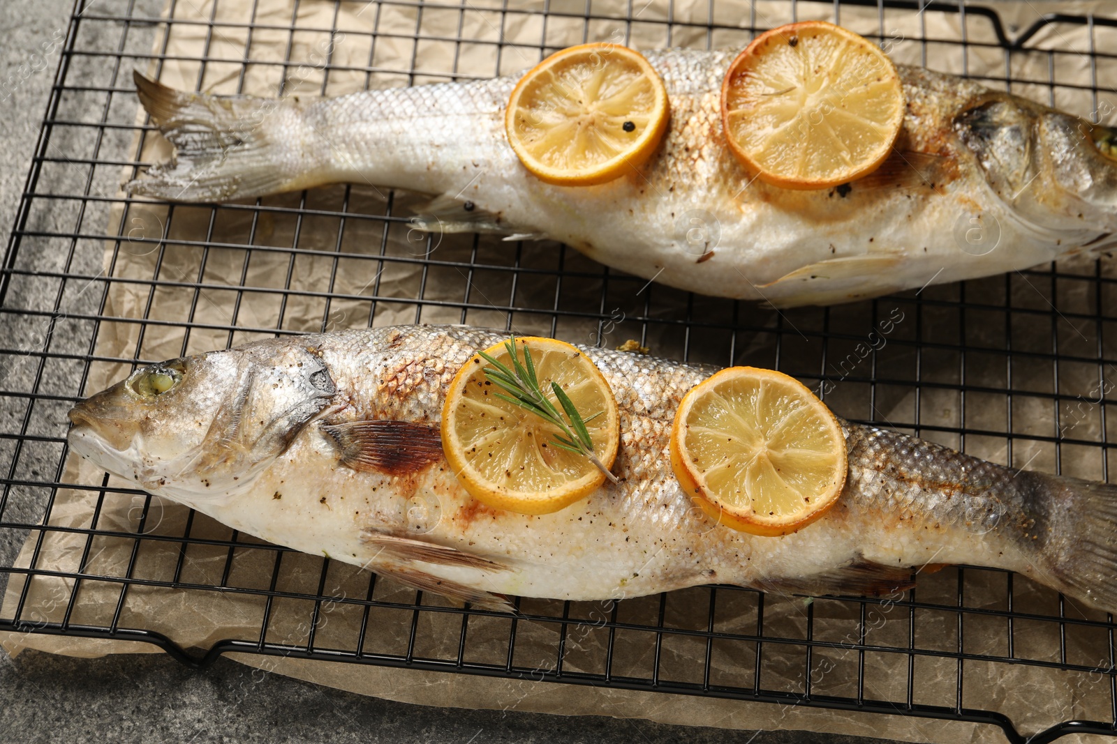 Photo of Baked fish with lemon on grey textured table, closeup