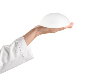 Doctor holding silicone implant for breast augmentation on white background. Cosmetic surgery