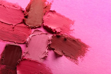 Photo of Smears of beautiful lipsticks on pink background, closeup