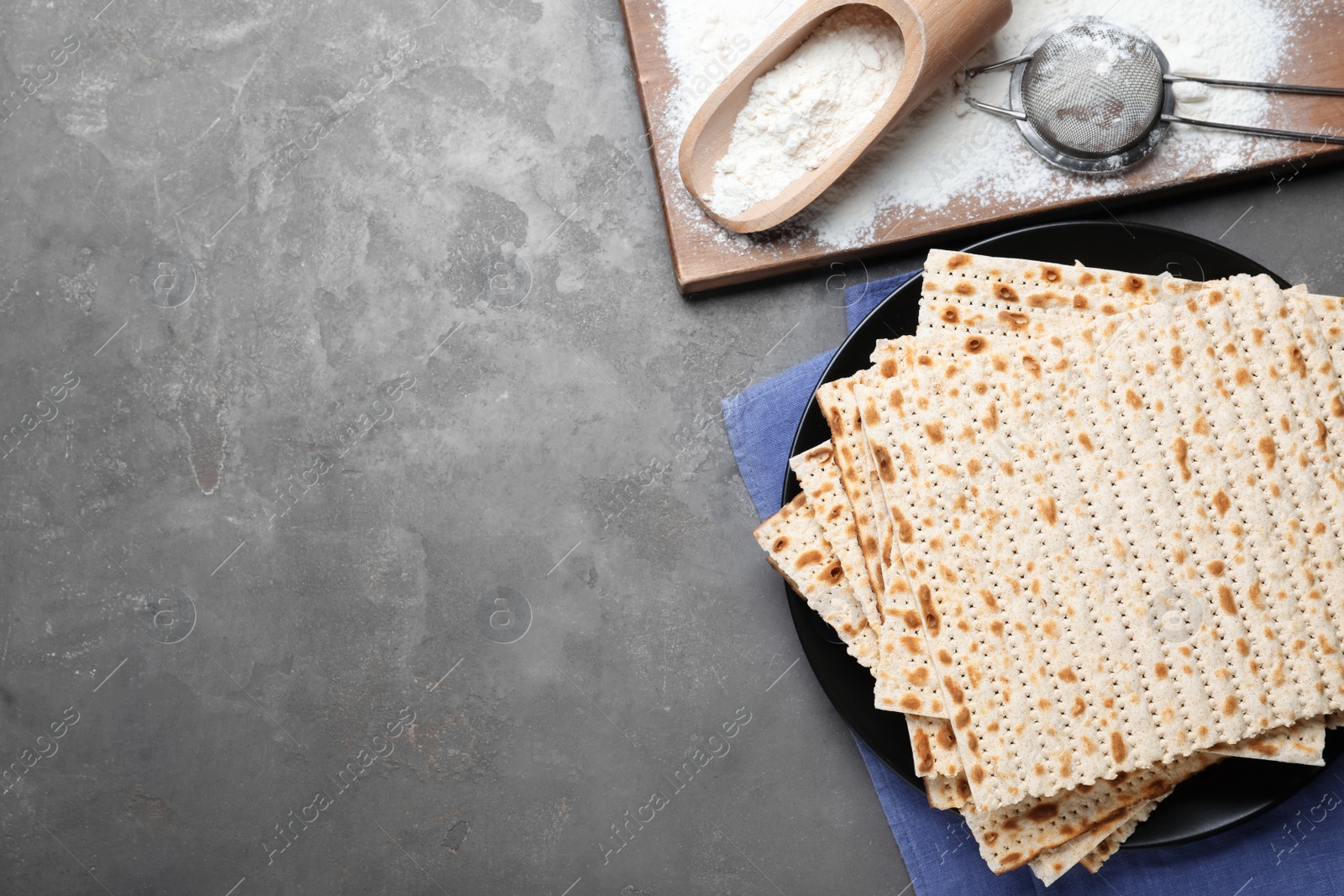 Photo of Flat lay composition with stack of traditional matzos on grey table. Space for text