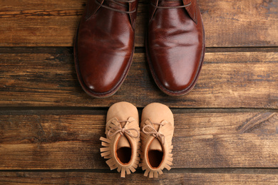 Photo of Dad and son's shoes on wooden background, flat lay. Happy Father's Day