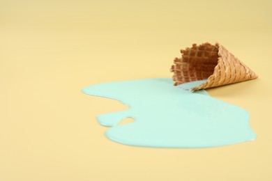 Photo of Melted ice cream and wafer cone on beige background. Space for text