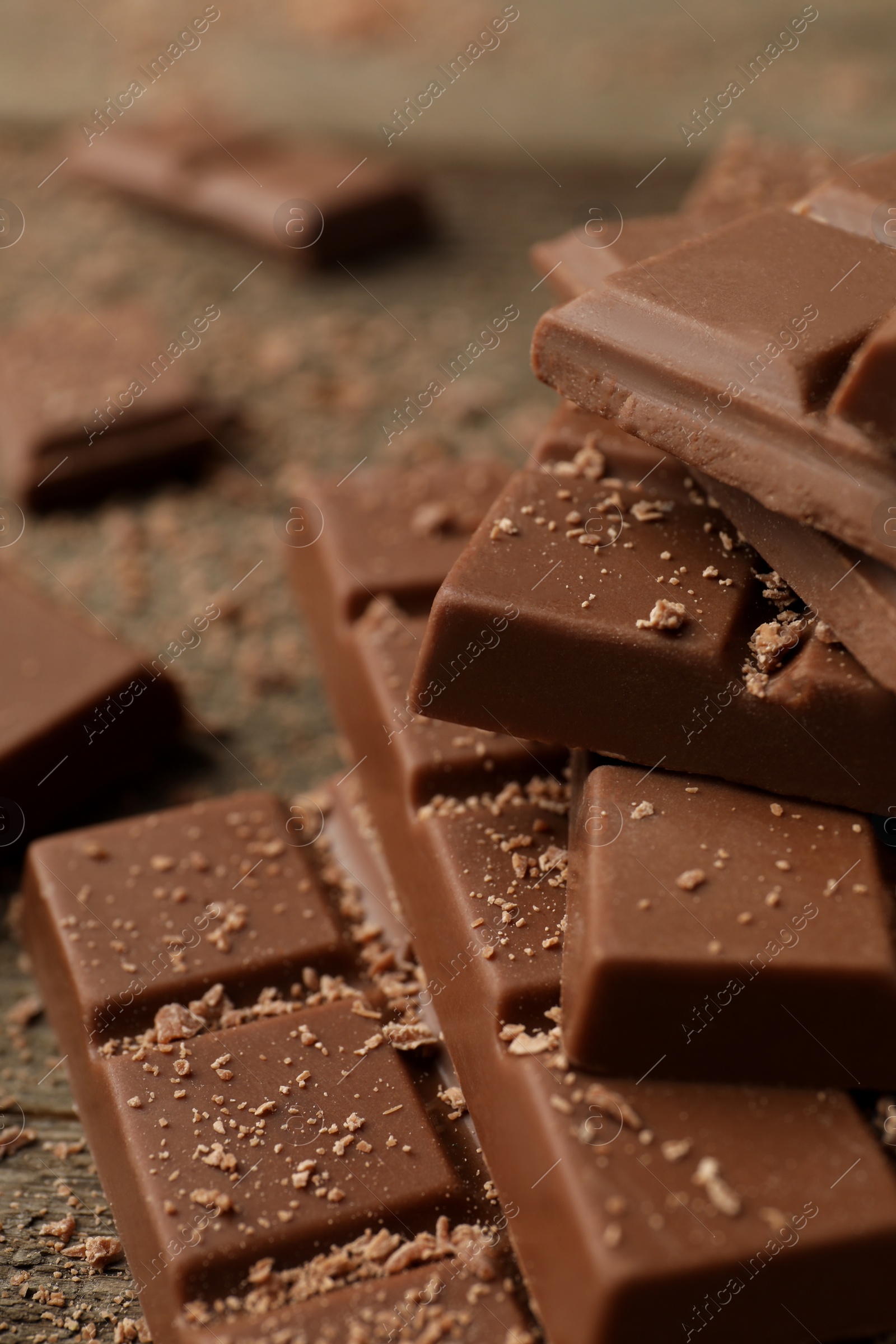 Photo of Pieces of tasty chocolate on wooden table, closeup