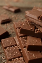Photo of Pieces of tasty chocolate on wooden table, closeup