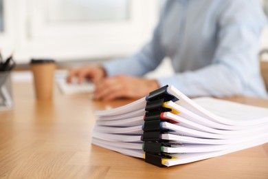 Photo of Man working at wooden table in office, focus on documents. Space for text