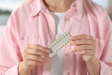 Photo of Woman holding blister of oral contraception pills, closeup