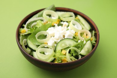 Bowl of tasty salad with leek and cheese on green table, closeup