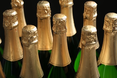 Photo of Many bottles of champagne on dark background, closeup