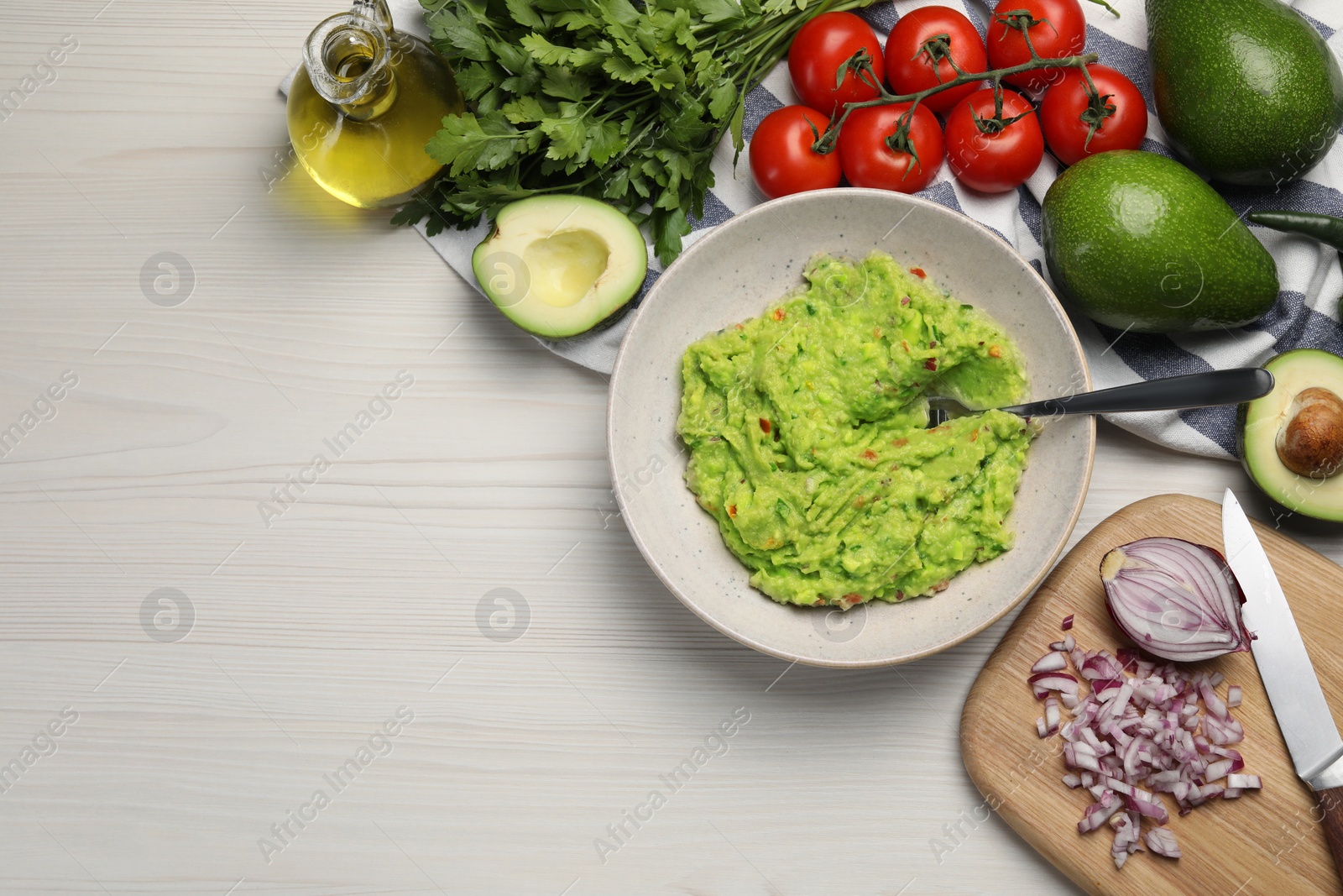 Photo of Delicious guacamole in bowl and ingredients on white wooden table, flat lay. Space for text