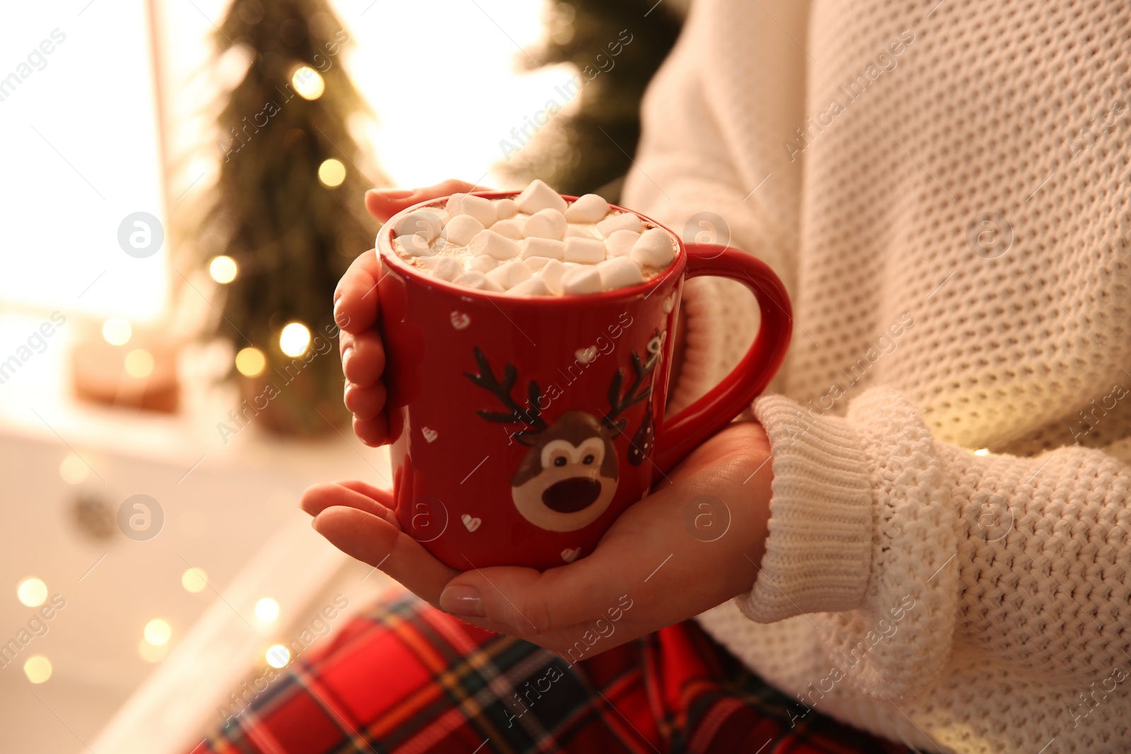 Photo of Woman holding cup of hot drink with marshmallow indoors, closeup