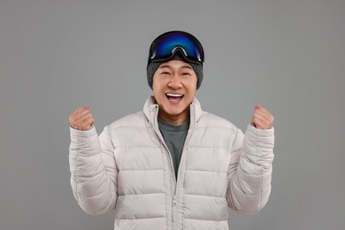Photo of Winter sports. Excited man with ski goggles on grey background